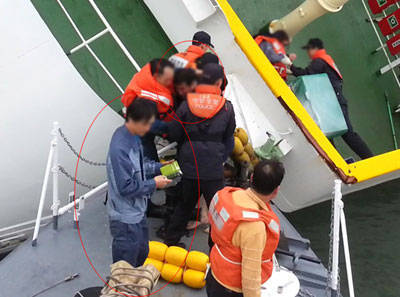 세월호 침몰 당시 선장 이준석과 1등 항해사 강원식을 구하고 있는 해경의 모습, 강원식은 핸드폰을 확인하고 있다. 