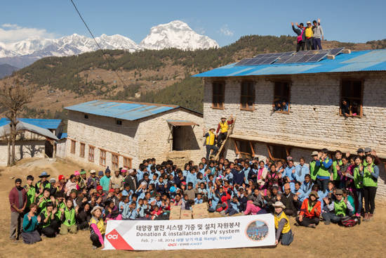 2014년 2월 OCI 자원봉사자들이 네팔 먀그디 지역 낭기마을의 히만찰 종합학교에 1.1kW 급 태양광패널을 설치하고 마을 주민들과 EWB-KAIST과 함께 기념사진을 촬영하고 있다. <사진=OCI 제공></div> 