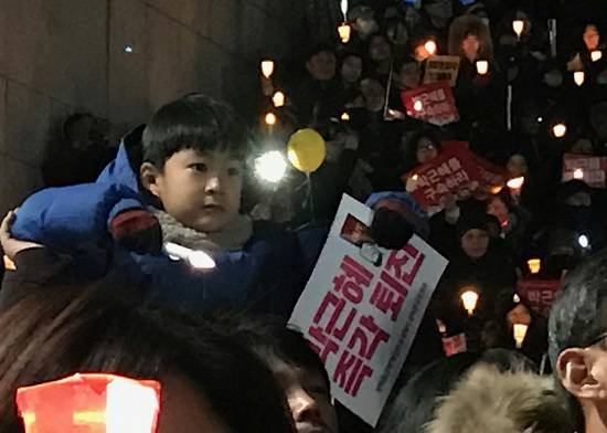 아버지 목마를 탄 광화문역에서 광장으로 올라가는 계단에서 촛불집회 무대를 바라보고 있다. 