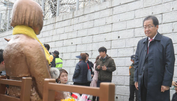 자유한국당 대선주자인 홍준표 경상남도지사가 22일 부산 동구 일본영사관 앞 소녀상을 방문해 국화 한 송이를 바친 뒤 소녀상을 바라보고 있다.<사진=연합뉴스></div> 