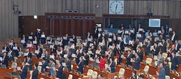  6일 새벽 열린 국회 본회의에서 2018년도 예산안이 통과될 때 자유한국당 의원들이 항의 팻말을 들고 자리에 서 있다. <사진=연합뉴스> 