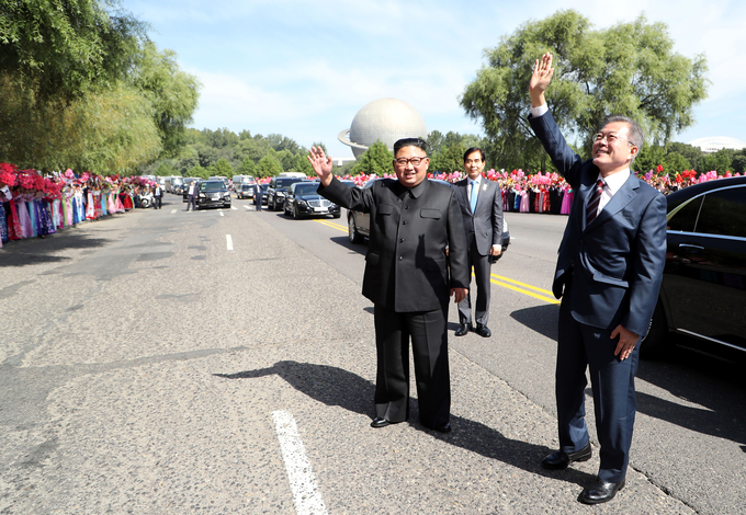 문재인 대통령과 김정은 국무위원장이 18일 평양 순안공항에서 평양시내로 향하는 차량에서 내려 환영 인파를 향해 인사하고 있다.  ⓒ평양사진공동취재단