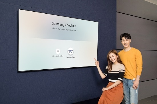삼성디지털프라자 용인 구성점에서 모델들이 2018년형 삼성 QLED TV 내에 탑재된 T-커머스(T-Commerce)  전용 결제 시스템 '삼성 체크아웃(Samsung Checkout)'에 도입된 '삼성페이' 간편결제 서비스를 소개하고 있다.<사진=삼성전자 제공>