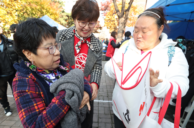 KT 방한복 나눔 행사에 참여한 주민들이 KT 임직원들과 함께 겨울 한파를 대비한 방한복을 고르고 있다. <사진=KT 제공>