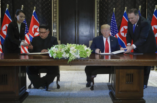 북미정상회담이 열린 12일 오후 싱가포르 센토사 섬 카펠라호텔에서 미국 도널드 트럼프 대통령과 북한 김정은 국무위원장이 공동합의문에 서명하고 있다.[스트레이츠타임스 홈페이지 캡처]