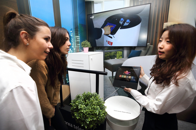 25일(현지시간) KT 전시관 내 5G AI 호텔 로봇 존에서 관람객이 AI 호텔 로봇 서비스를 체험하고 있다. <사진=KT 제공>