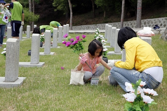 지난 18일 서울 동작구 국립서울현충원에서 실시된 묘역 정화 봉사활동에서 임직원 가족들이 묘역을 단장하고 있다 <사진=현대엔지니어링 제공>