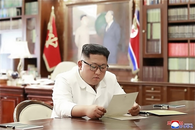 조선중앙통신이 23일 홈페이지에 공개한 사진에서 김정은 북한 국무위원장이 집무실로 보이는 공간에서 트럼프 대통령의 친서를 읽는 모습.<사진=연합뉴스>