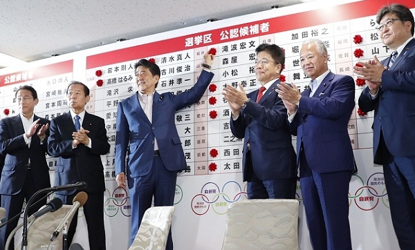 아베 신조 일본 총리가 7월 21일 자민당본부 개표센터에서 일본 참의원 선거 당선자 이름에 장미꽃을 붙이고 있다.[도쿄 교도=연합뉴스]