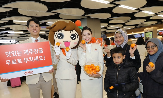 제주항공은 2일 김포국제공항 국내선 카운터 앞에서 여행객을 대상으로 감귤을 나눠주는 행사를 진행했다. <사진=제주항공 제공>