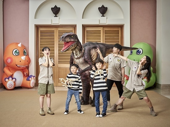 제주신라호텔 '쥬라기 클래스'에 참여한 아이들이 '벨로시랩터' 공룡과 만나 함께 사진을 찍고 있다. <사진=호텔신라 제공>