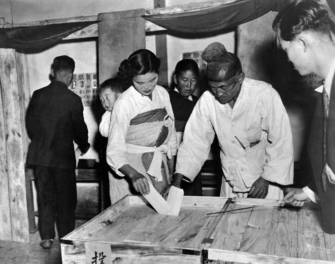 1948년 아이 업은 여인과 할아버지가 나무로 된 투표상자에 투표지를 넣고 있다. <사진=행정자치부 국가기록원 제공>