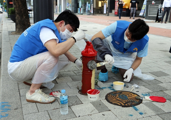 KCC 행복나눔 봉사단 직원들이 소화전에 색을 칠하고 있다. <사진=KCC 제공>
