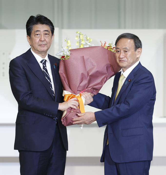 아베 신조 총리가 차기 총리에 당선된 스가 장관에게 꽃다발을 전달하고 있다. <사진=연합뉴스>
