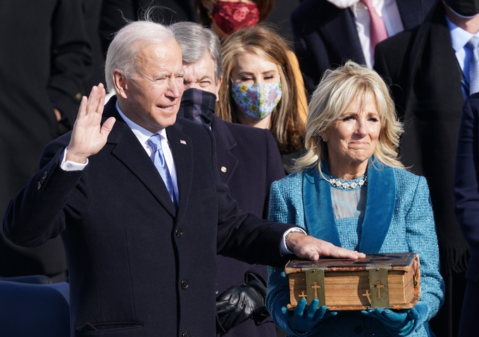 조 바이든 미국 46대 대통령이 20일(현지시간) 수도 워싱턴DC 연방 의사당 앞 야외무대에서 개최된 취임식에서 부인 질 여사가 지켜보는 가운데 두툼하고 오래된 성경 위에 왼손을 얹고 취임 선서를 하고 있다.  <사진=연합뉴스>