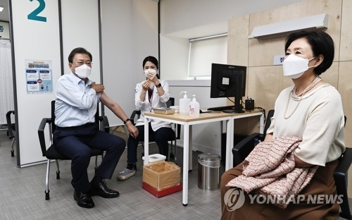 문재인 대통령이 15일 서울 국립중앙의료원 코로나19 중앙예방접종센터에서 코로나19 백신 추가 접종을 받고 있다. 김정숙 여사(오른쪽)가 차례를 기다리고 있다. 