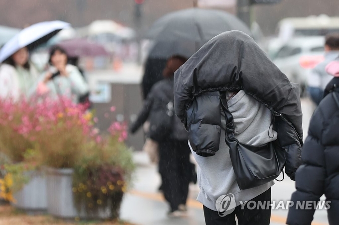 전국 곳곳 비가 예보된 28일 오후 서울 광화문광장 인근에서 시민이 겉옷으로 비를 막으며 이동하고 있다. 2022.11.28