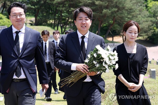 15일 오전 광주 북구 국립 5·18 민주묘지에서 개혁신당 이준석 대표와 당선인들이 국화를 들고 이동하고 있다. 이 대표는 경남 김해에서 재배한 국화 1천송이를 직접 공수해 995기에 달하는 개별 묘지에 헌화·참배했다. [사진=연합뉴스]