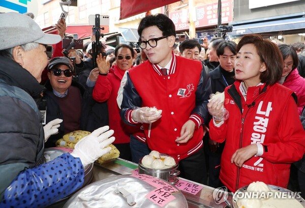 국민의힘 한동훈 비상대책위원장 겸 총괄선대위원장이 19일 오후 나경원 동작을 후보와 함께 동작구 남성사계시장을 찾아 만두를 먹고 있다. [사진=연합뉴스]