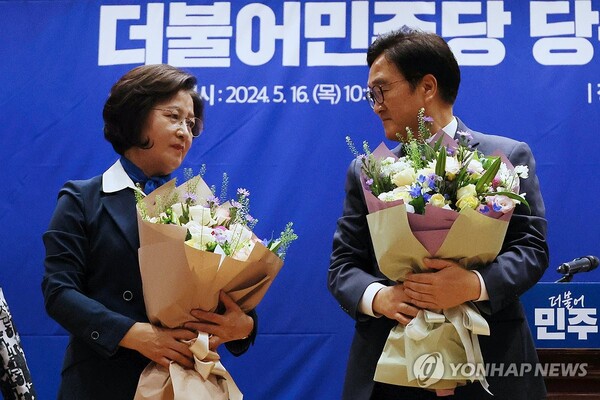 더불어민주당 국회의장 후보 경선에 나선 우원식(오른쪽)·추미애 후보가 16일 국회 의원회관에서 열린 제22대 전반기 국회의장단 후보 선출을 위한 당선자 총회에서 경선 결과가 발표된 뒤 꽃다발을 들고 서 있다. [사진=연합뉴스]