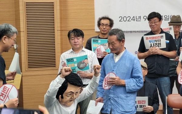 "무릎 꿇고 혼나고 있는 윤석열 대통령" '윤석열 퇴진 부산운동본부'가 24일 부산시의회 브리핑룸에서 연 "윤석열퇴진 사회대개혁 9.28 부산시국대회(12치) 개최 선포 및 하반기 사업방향 발표 기자회견'을 마치며, 윤석열 대통령 가면을 쓴 시민이 무릎을 꿇고 사죄하는 가운데 '퇴진' 스티커를 붙이는 상징행동(퍼포먼스)을 하고 있다.[사진=정하룡 기자]