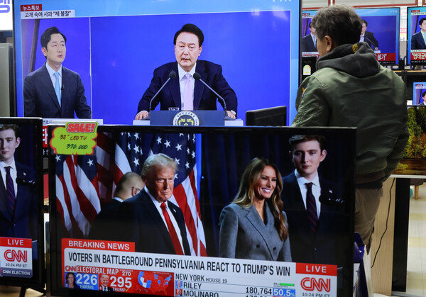 7일 서울 용산구 한 가전매장에서 시민이 윤석열 대통령의 대국민 담화·회견 관련 방송을 보고 있다. 앞 TV에서는 도널드 트럼프 미국 대통령 당선인 관련 보도가 나오고 있다.[사진=연합뉴스]