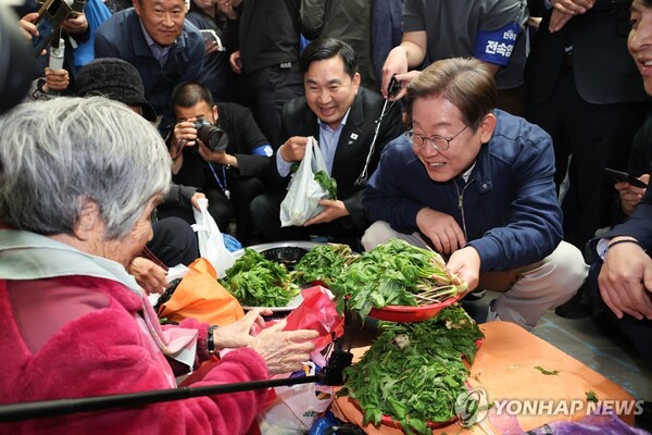 더불어민주당 이재명 대선 후보가 '골목골목 경청투어' 접경지역 방문 이틀째인 2일 강원도 인제군 원통전통시장에서 엄나무순을 사며 어르신과 대화하고 있다. [사진=연합뉴스]