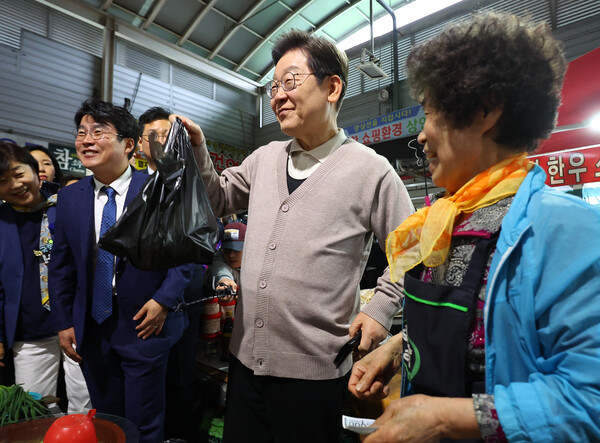 더불어민주당 이재명 대선 후보가 제3차 골목골목 경청투어로 경북지역 방문에 나선 9일 경북 영천시 영천공설시장을 찾아 한 가게에서 영천사랑상품권으로 말린 고추를 구매하고 있다. [사진=연합뉴스]