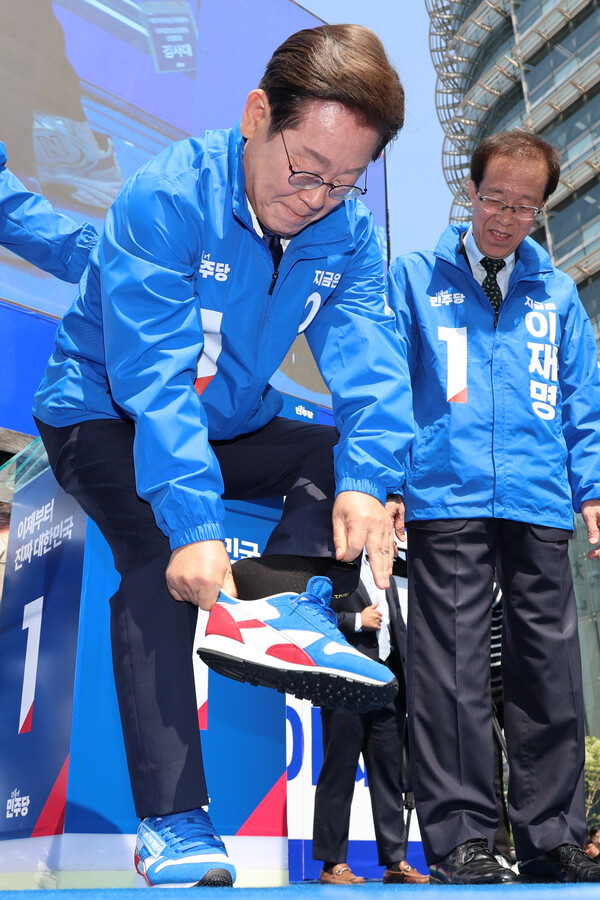 더불어민주당 이재명 대선 후보가 6·3 대통령선거 공식 선거운동 첫날인 12일 서울 광화문 청계광장에서 열린 중앙선대위 출정식 및 첫 유세에서 구두를 벗고 운동화로 갈아신고 있다. [사진=연합뉴스]