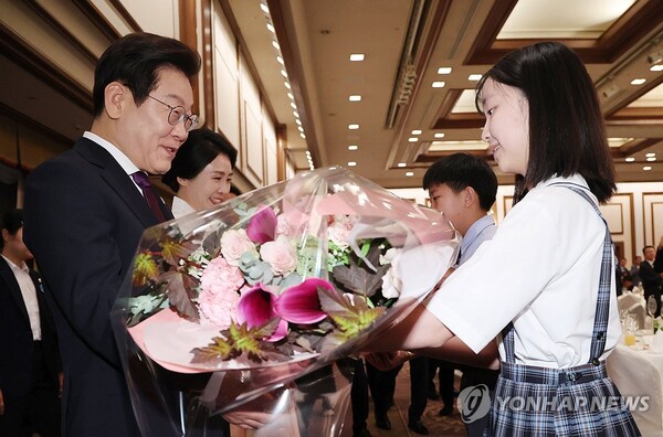 이재명 대통령과 김혜경 여사가 23일 일본 도쿄의 한 호텔에서 열린 재일동포 오찬 간담회에 참석해 화동으로부터 꽃다발을 받고 있다. [사진=연합뉴스]
